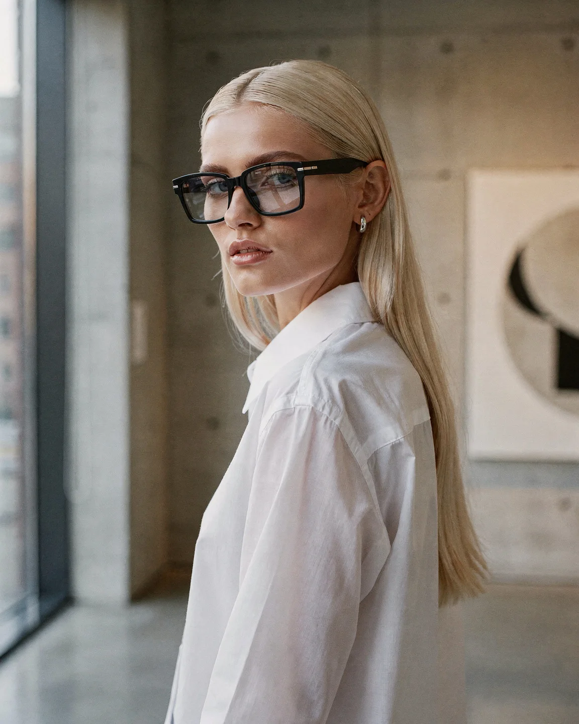 Woman in black square glasses in a gallery