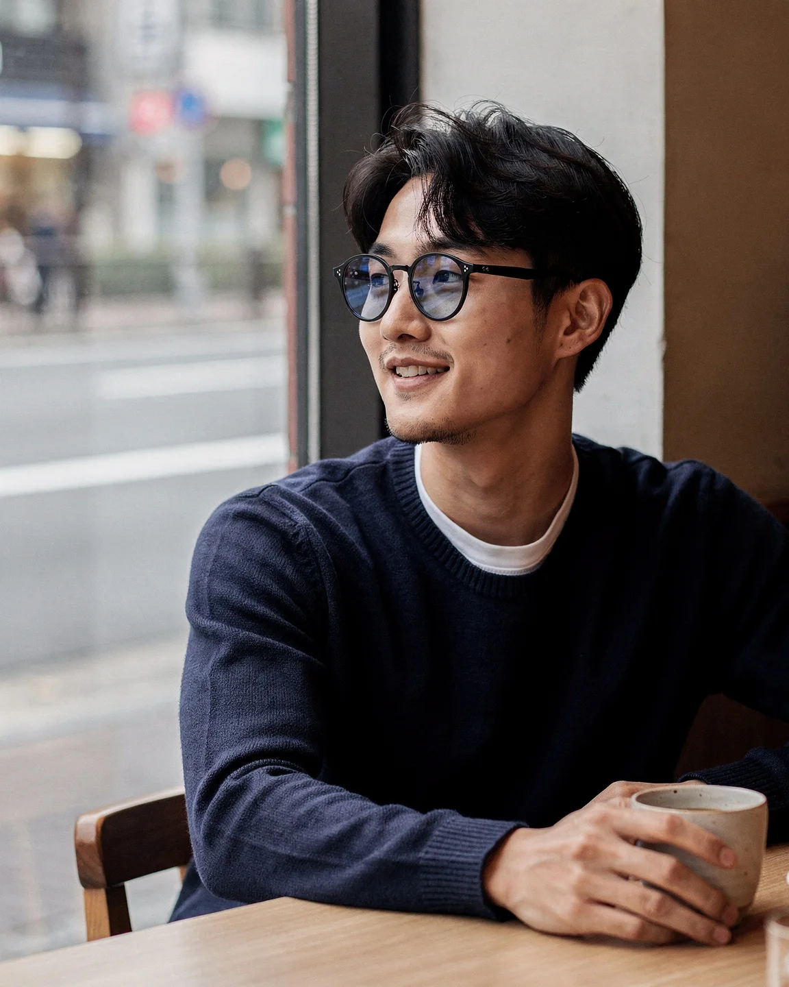 Man in round black glasses in a cafe